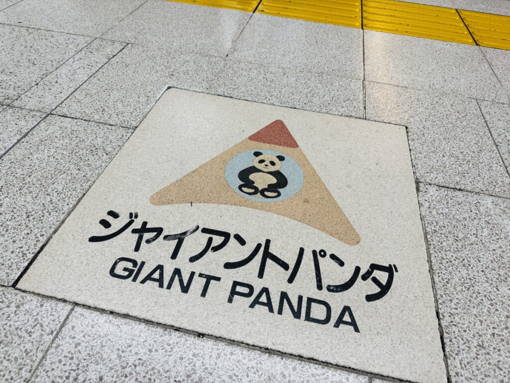 Cute directional sign inside JR Ueno Station pointing the way to Ueno Zoo, with panda illustrations.