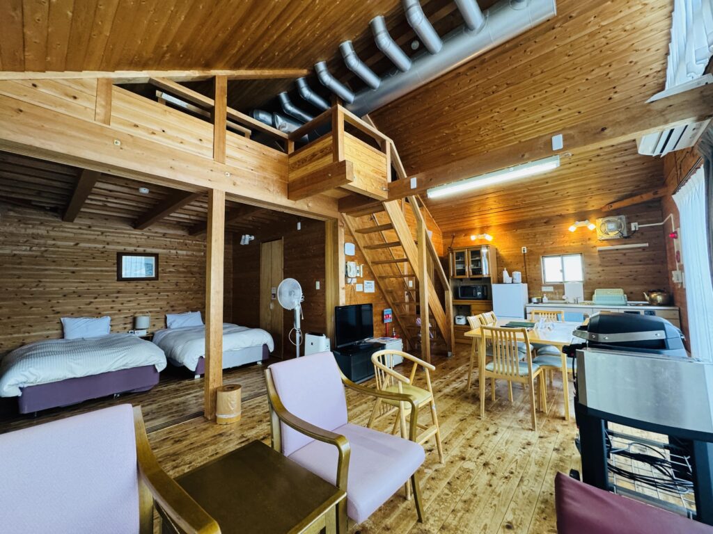 Interior of a Kyukamura Fuji cottage with a bright living area, bedroom space, and a loft above.
