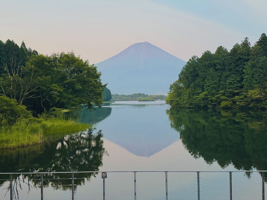 Mt. Fuji and nearby trees reflected like a mirror on the lake, seen from the renovated Fujaku Terrace at Lake Tanuki.
