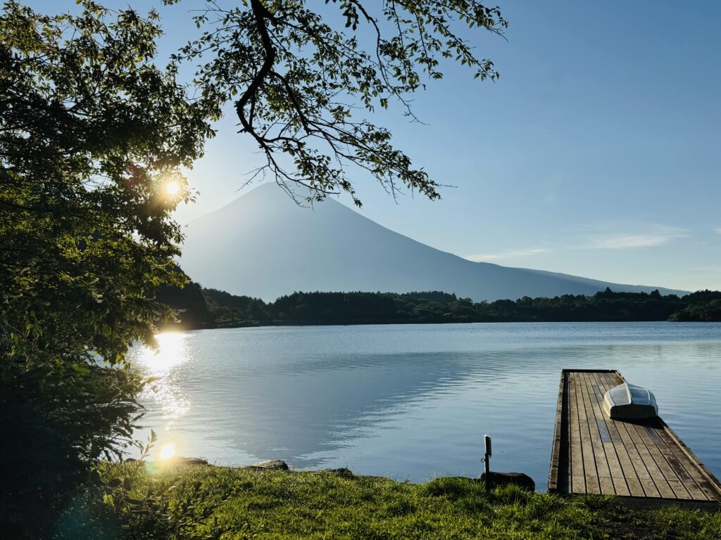 Mt. Fuji from Lake Tanuki’s shore, softly mirrored on the rippling lake surface.