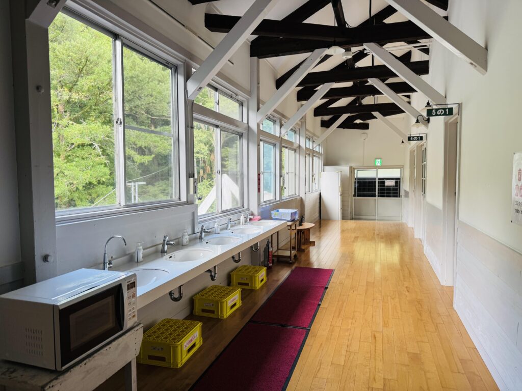 Second-floor hallway of Yamabiko-so Inn in Nishi-Izu, with sinks outside the former classrooms