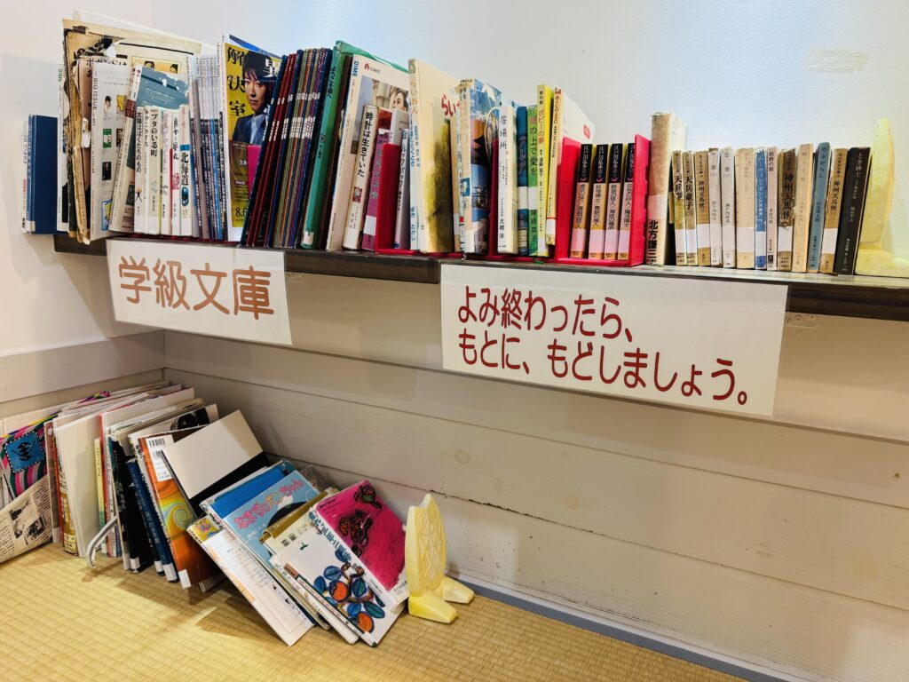 Shared book corner at Yamabiko-so Inn in Nishi-Izu, styled like a classroom bookshelf