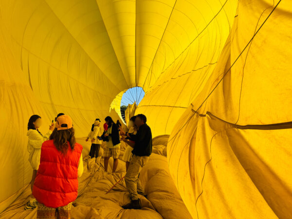 Participants stepping inside the deflated hot air balloon after landing in Cairns, smiling as they explore the colorful interior fabric.