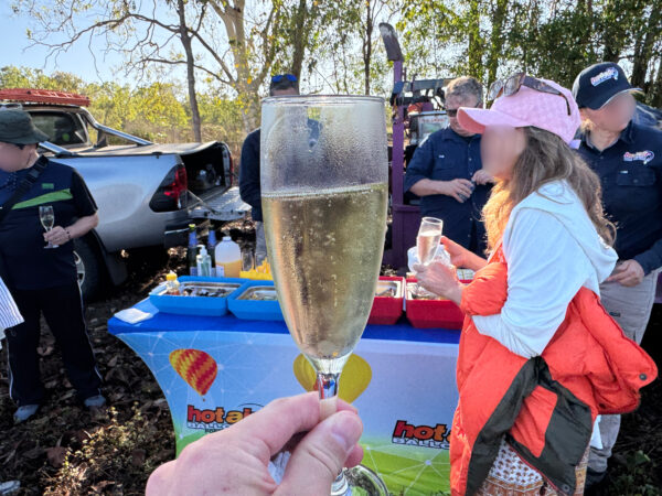 Post-flight gathering after the Cairns hot air balloon tour, with champagne, soft drinks, fruits, and light snacks on the table as guests relax and chat.