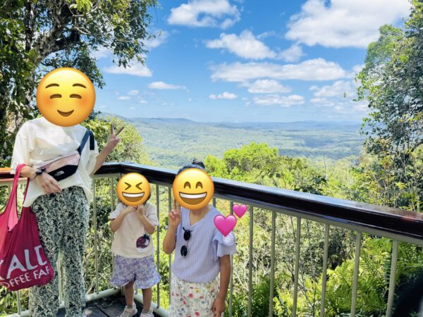 Family taking a commemorative photo at Skyrail’s Red Peak Station with the World Heritage rainforest in the background.