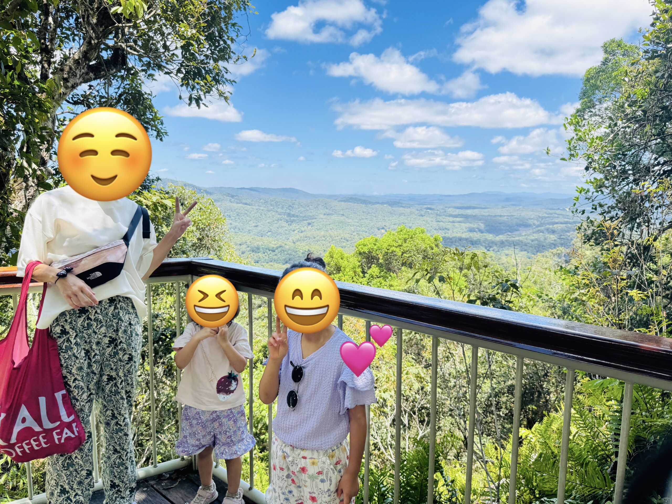 Family taking a commemorative photo at Skyrail’s Red Peak Station with the World Heritage rainforest in the background.