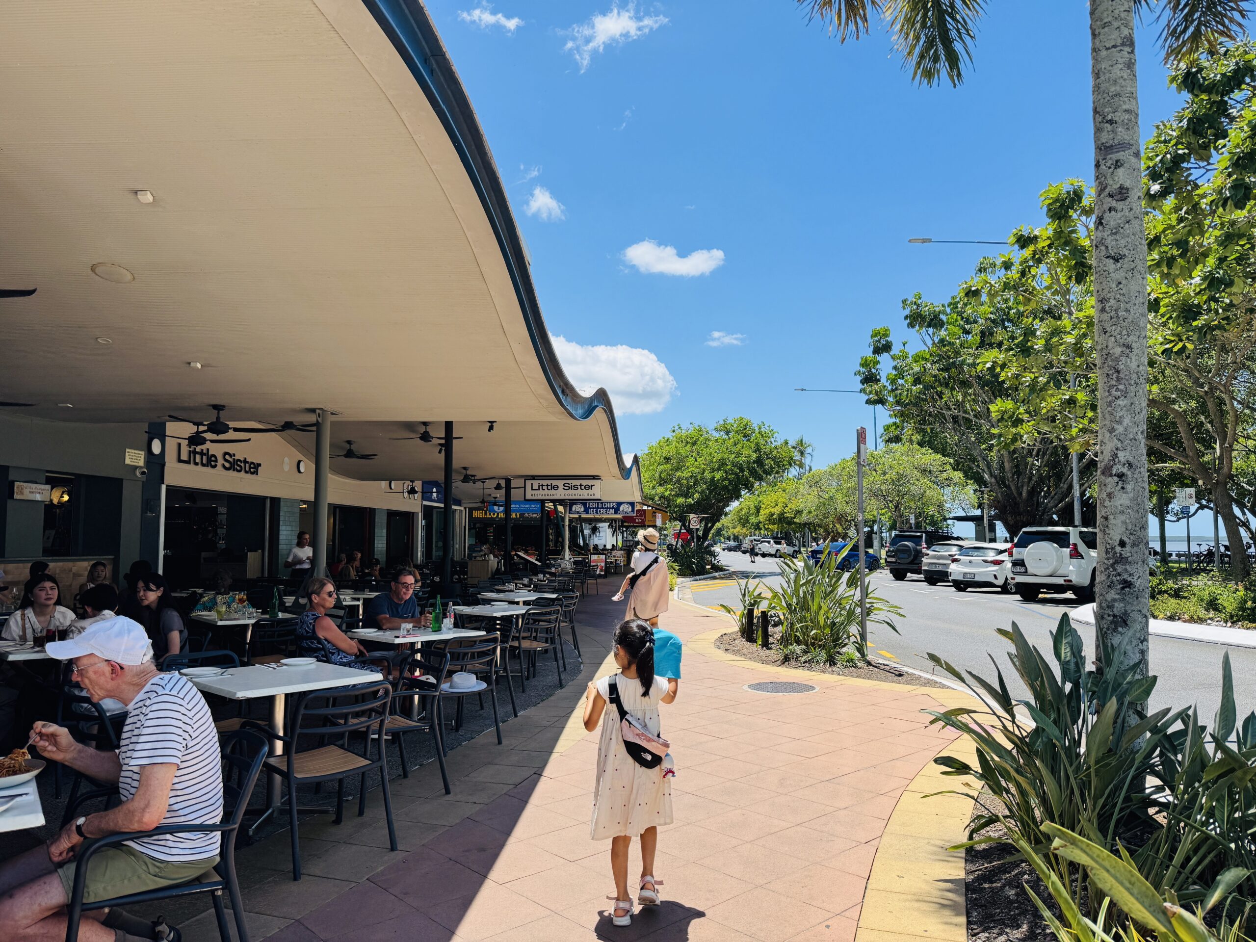 ケアンズの街中で海沿いの道を家族で散策する様子